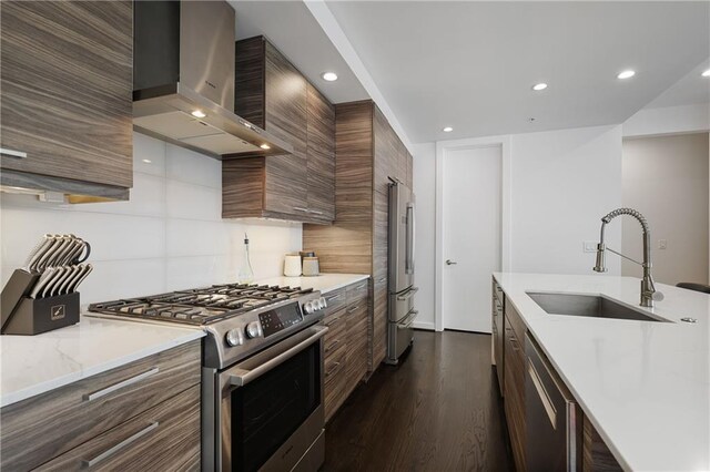 kitchen featuring sink, dark wood-type flooring, appliances with stainless steel finishes, decorative backsplash, and wall chimney exhaust hood