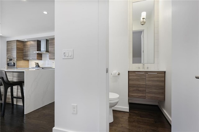 bathroom featuring vanity, wood finished floors, recessed lighting, toilet, and backsplash