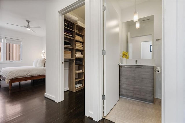 bathroom with baseboards, vanity, a ceiling fan, and wood finished floors