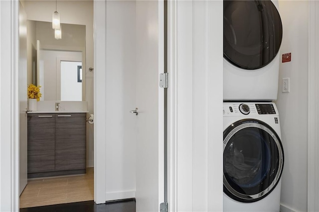 laundry room featuring stacked washer and clothes dryer, wood finished floors, and laundry area