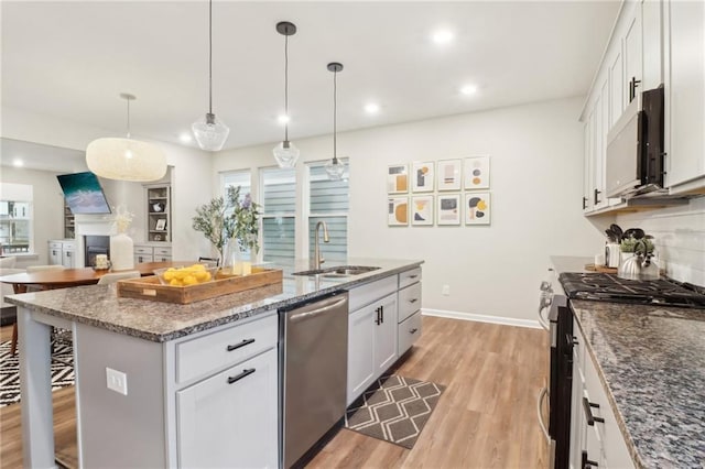 kitchen with sink, stainless steel appliances, a kitchen breakfast bar, white cabinets, and a center island with sink