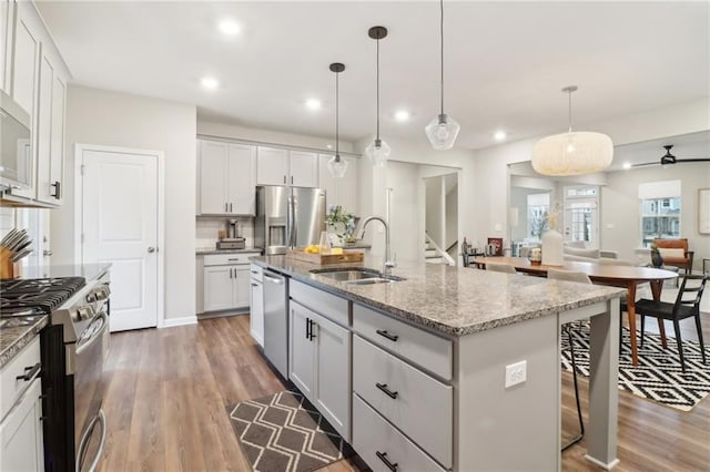 kitchen featuring sink, white cabinetry, decorative light fixtures, an island with sink, and stainless steel appliances