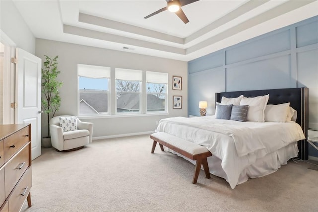 carpeted bedroom featuring a tray ceiling and ceiling fan