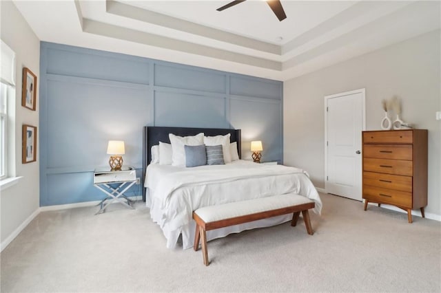 bedroom with a raised ceiling, light carpet, and ceiling fan