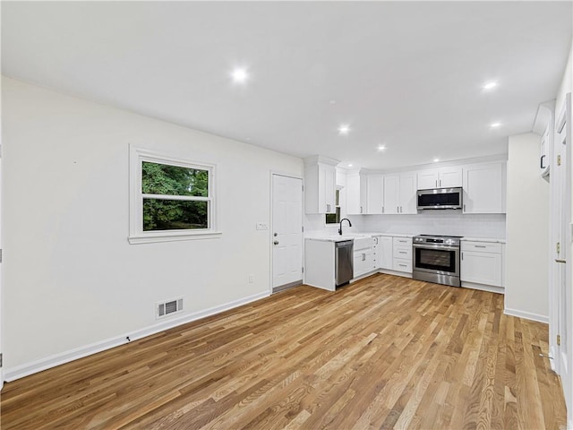 466 Thackery Pl SW, Atlanta, GA 30311 - kitchen featuring appliances with stainless steel finishes, light countertops, light wood-style floors, white cabinets, and tasteful backsplash