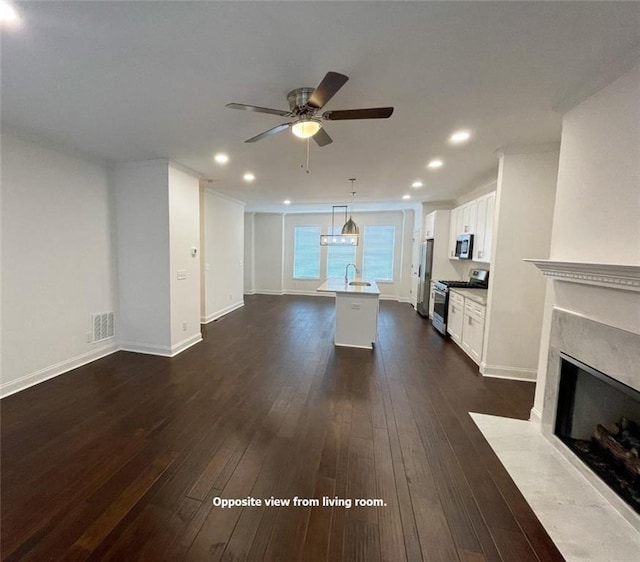 unfurnished living room featuring ceiling fan, dark wood-type flooring, a high end fireplace, and sink