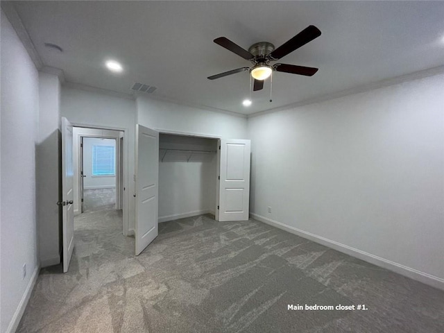 unfurnished bedroom with ornamental molding, ceiling fan, a closet, and carpet