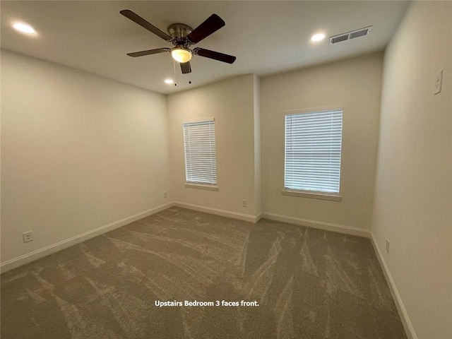 spare room with ceiling fan and dark colored carpet