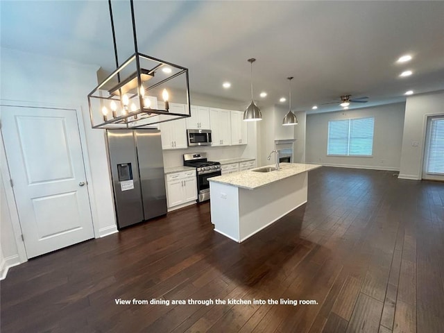 kitchen featuring a center island with sink, appliances with stainless steel finishes, pendant lighting, and white cabinetry