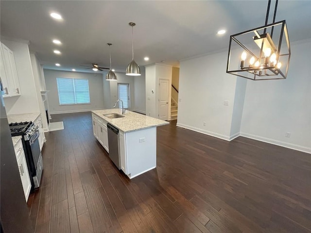 kitchen with stainless steel appliances, white cabinetry, ceiling fan with notable chandelier, hanging light fixtures, and a kitchen island with sink