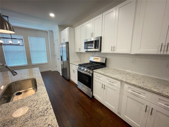 kitchen with light stone counters, pendant lighting, stainless steel appliances, white cabinets, and sink