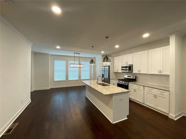 kitchen with stainless steel appliances, white cabinets, an island with sink, and hanging light fixtures