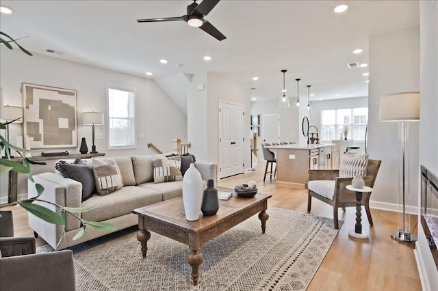 living area with a ceiling fan, visible vents, light wood-style flooring, and recessed lighting