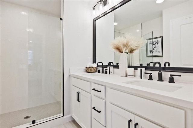 bathroom featuring double vanity, a sink, and a shower stall