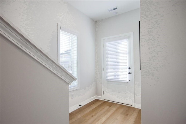 entryway with light wood-style floors, baseboards, plenty of natural light, and visible vents