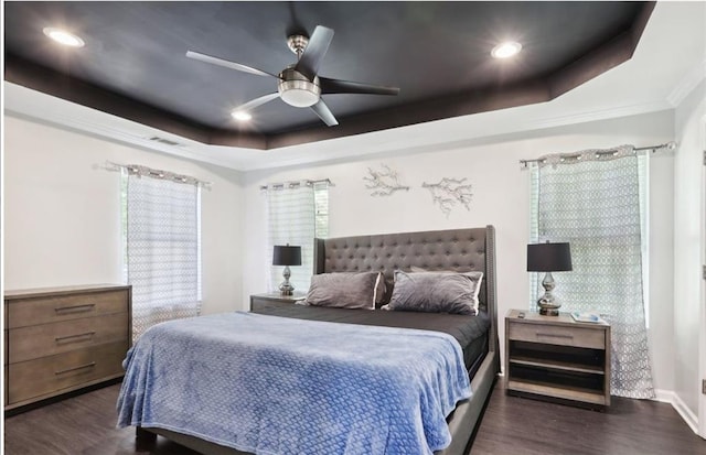 bedroom with dark wood-style flooring, visible vents, recessed lighting, and a tray ceiling