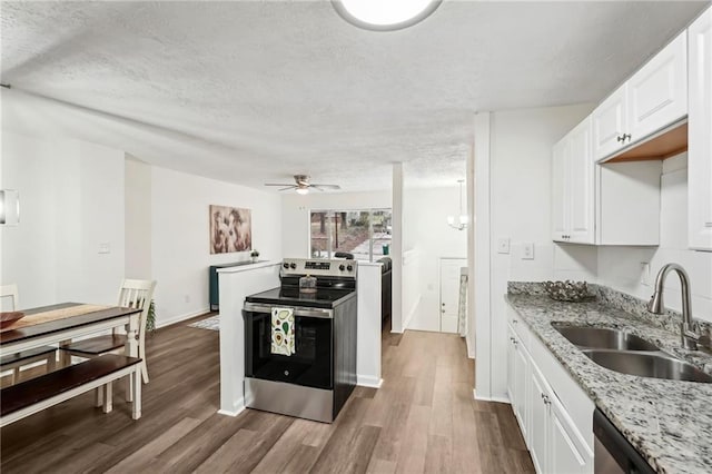 kitchen featuring a textured ceiling, stainless steel appliances, a sink, white cabinetry, and dark wood finished floors