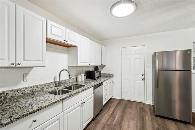 kitchen featuring white cabinets, appliances with stainless steel finishes, dark wood-style flooring, light stone countertops, and a sink