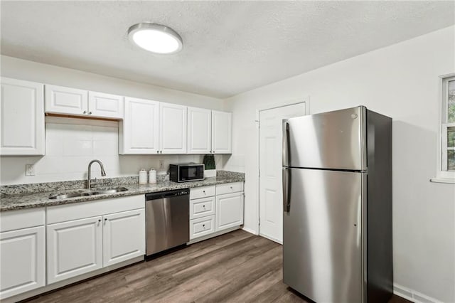 kitchen with appliances with stainless steel finishes, white cabinetry, and a sink