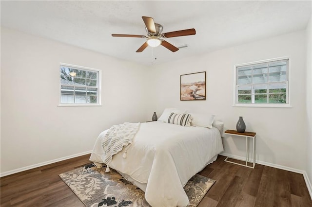 bedroom with multiple windows, visible vents, baseboards, and wood finished floors