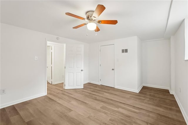 unfurnished room with ceiling fan, light wood-style flooring, visible vents, and baseboards