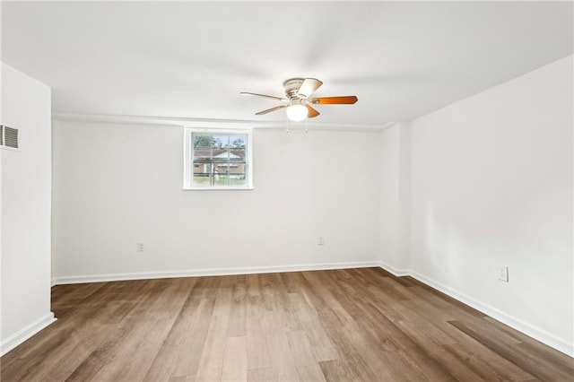 spare room featuring a ceiling fan, baseboards, visible vents, and wood finished floors