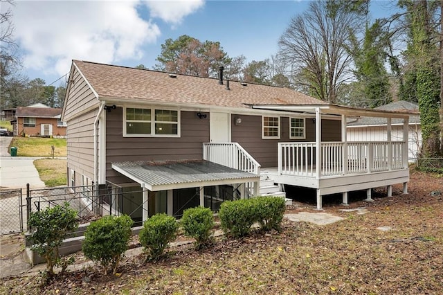 rear view of house with a shingled roof, fence, and a wooden deck