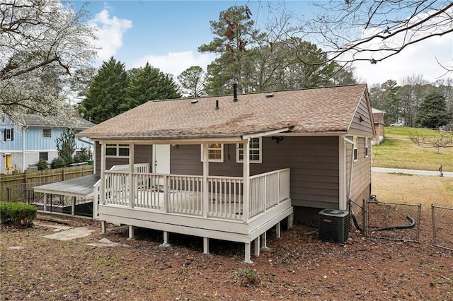 rear view of property with a deck, roof with shingles, fence, and central air condition unit