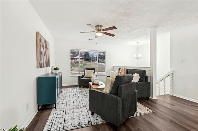 living area featuring visible vents, baseboards, wood finished floors, a textured ceiling, and ceiling fan with notable chandelier