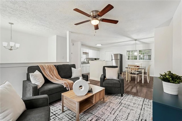 living area featuring a textured ceiling, ceiling fan with notable chandelier, and light wood-type flooring