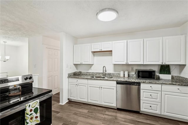 kitchen with light stone counters, stainless steel appliances, wood finished floors, a sink, and white cabinets