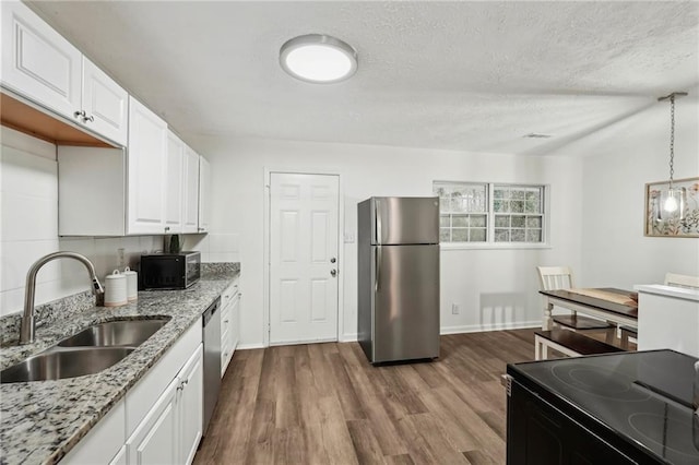 kitchen featuring dark wood-style flooring, appliances with stainless steel finishes, white cabinetry, a sink, and light stone countertops