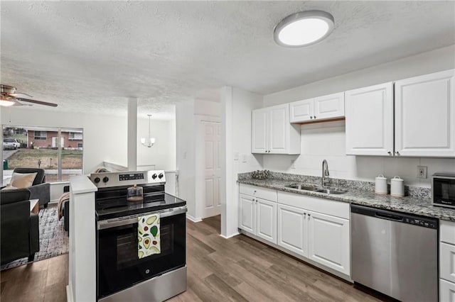 kitchen with a textured ceiling, appliances with stainless steel finishes, a sink, and wood finished floors