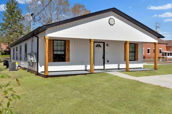 view of front facade featuring cooling unit, a porch, and a front yard