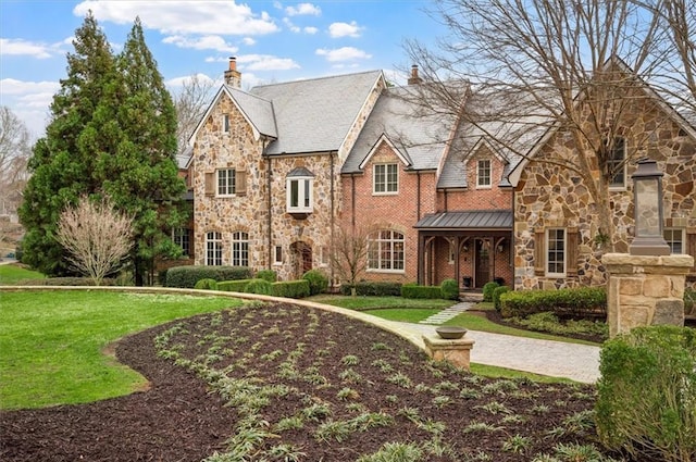 view of front facade with stone siding, a chimney, and a front lawn