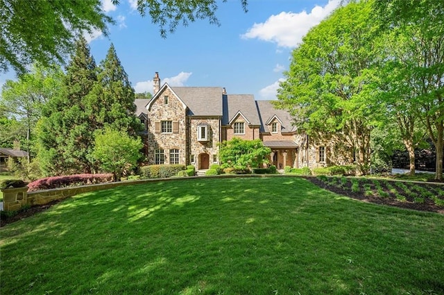 view of front of property featuring stone siding, a front yard, and a chimney