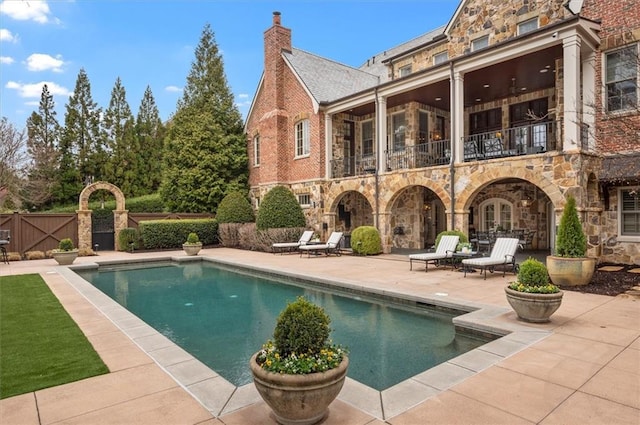 rear view of property with stone siding, a balcony, and a patio area