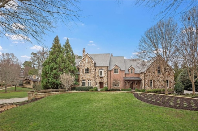 view of front of property with stone siding, a chimney, and a front lawn