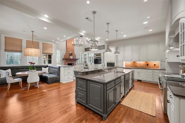 kitchen featuring gray cabinetry, a sink, high end range, open floor plan, and white cabinetry