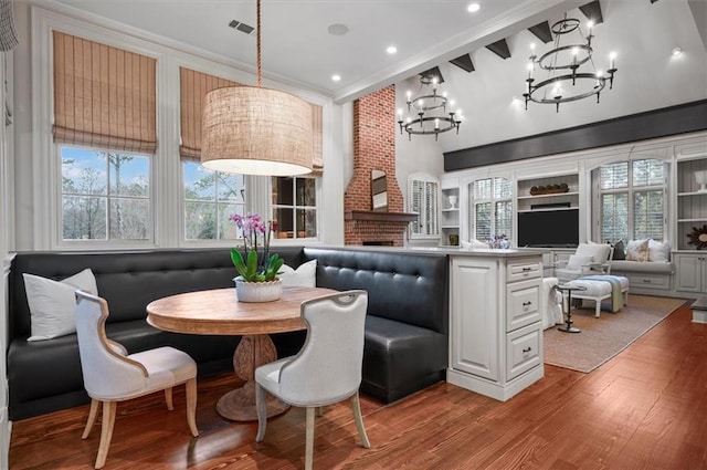 dining room featuring a chandelier, breakfast area, wood finished floors, plenty of natural light, and crown molding