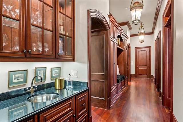 bar area with a sink, dark wood-style floors, and ornamental molding