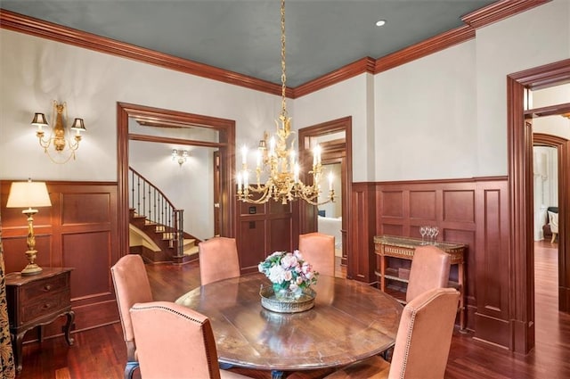 dining area with stairs, a chandelier, dark wood-style flooring, a decorative wall, and a wainscoted wall