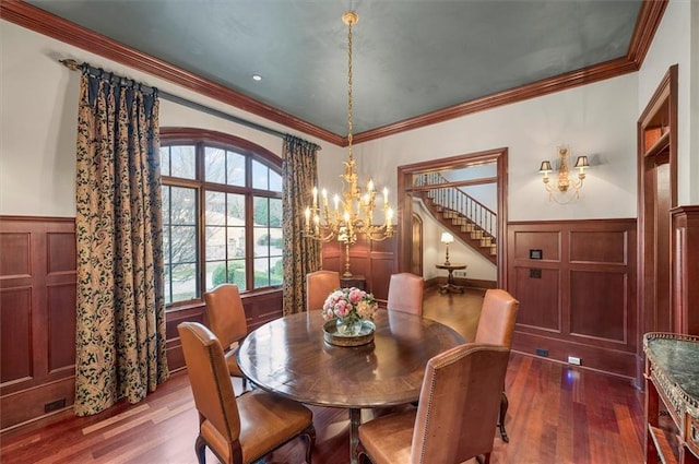dining room featuring a chandelier, dark wood-style floors, a wainscoted wall, a decorative wall, and stairs