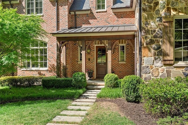 doorway to property with a standing seam roof, brick siding, and metal roof