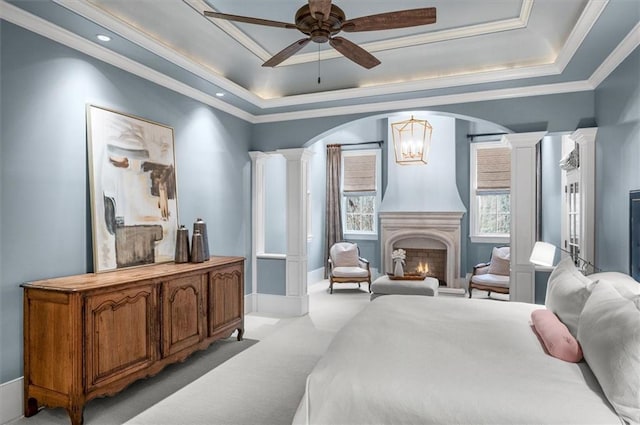 bedroom featuring ornate columns, a tray ceiling, arched walkways, a chandelier, and light carpet