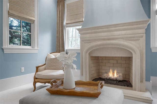 sitting room featuring a lit fireplace, healthy amount of natural light, and carpet