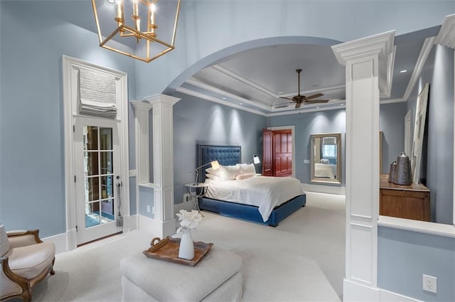 carpeted bedroom with decorative columns, crown molding, arched walkways, a tray ceiling, and a chandelier