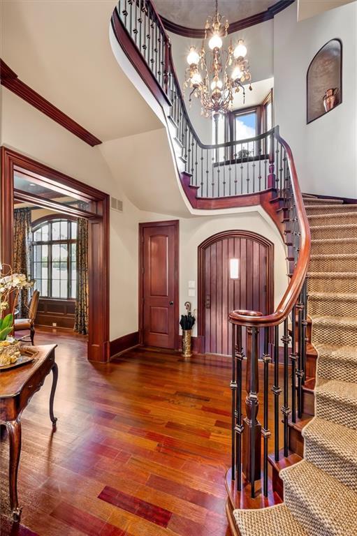 foyer with crown molding, stairs, wood finished floors, a chandelier, and baseboards