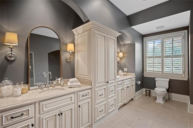 bathroom with double vanity, tile patterned floors, toilet, and baseboards