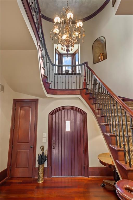 entryway featuring a high ceiling, wood finished floors, stairway, a chandelier, and baseboards